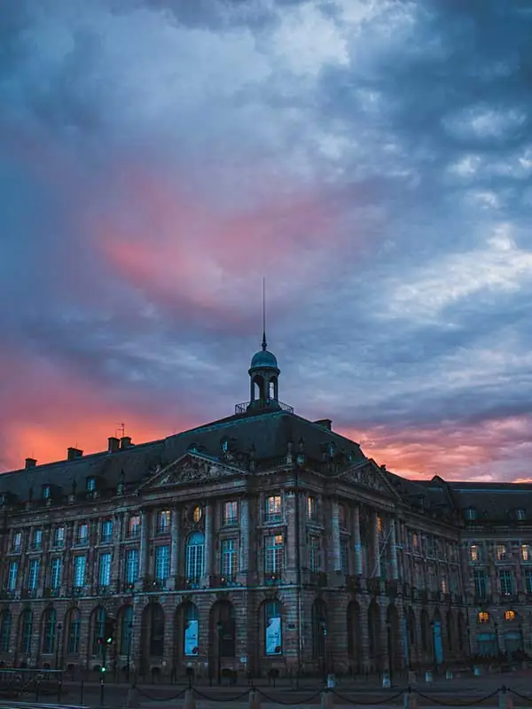 Façade classique du XVIIIe siècle à Bordeaux sous un ciel de crépuscule